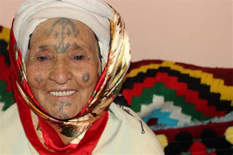 Smiling Amazigh woman with traditional tattoos on her forehead, cheeks and chin