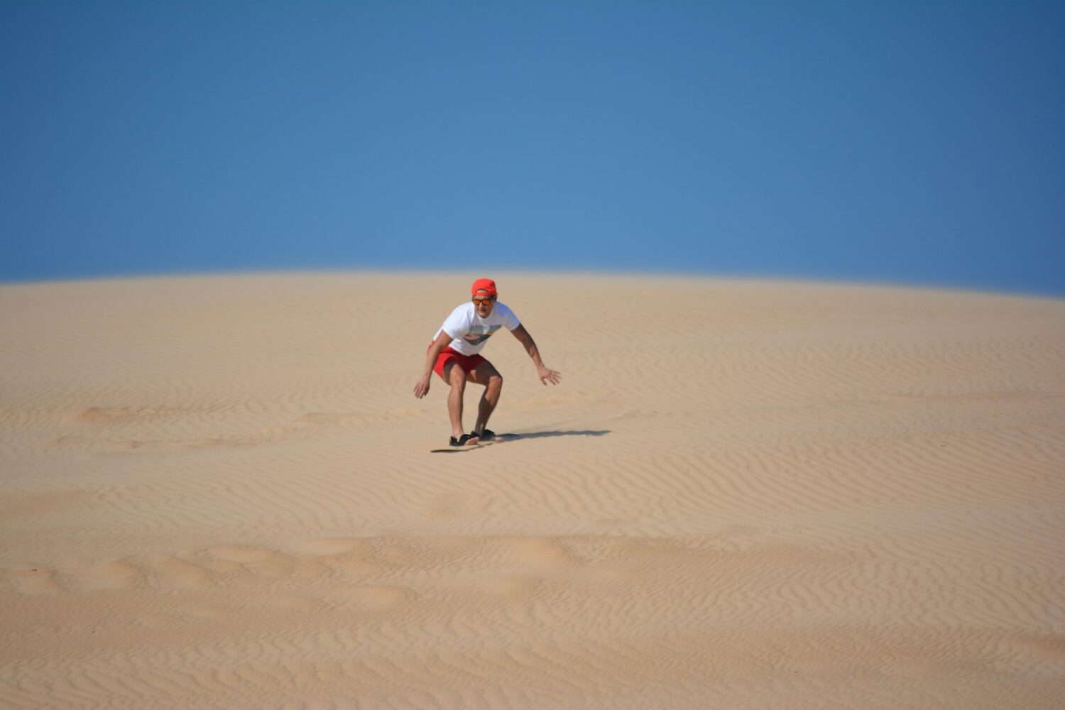 Sandboarding down a desert dune